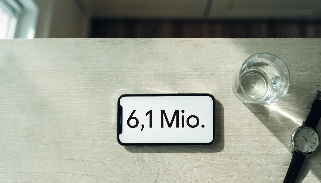 Ein Smartphone liegt mit dem Display nach unten auf einem Küchentisch, daneben stehen ein Glas Wasser und eine Armbanduhr.